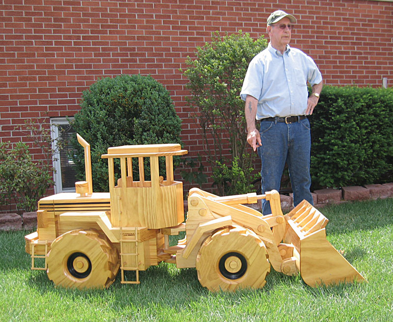 Chuck With His Wooden Tractor Chuck stands behind his wooden scale model articulated front end loader.