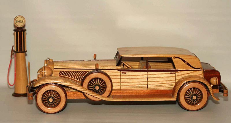 Wooden Duesenberg A sleek wooden Duesenberg pulls up to a vintage gravity-fed gasoline pump.