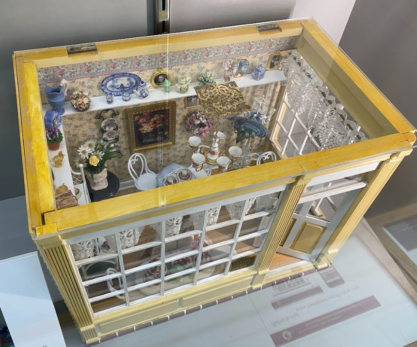 This small dollhouse built by Anita Kirwan is called the Cherry Tree House. The tiny shop is filled with delicious desserts.